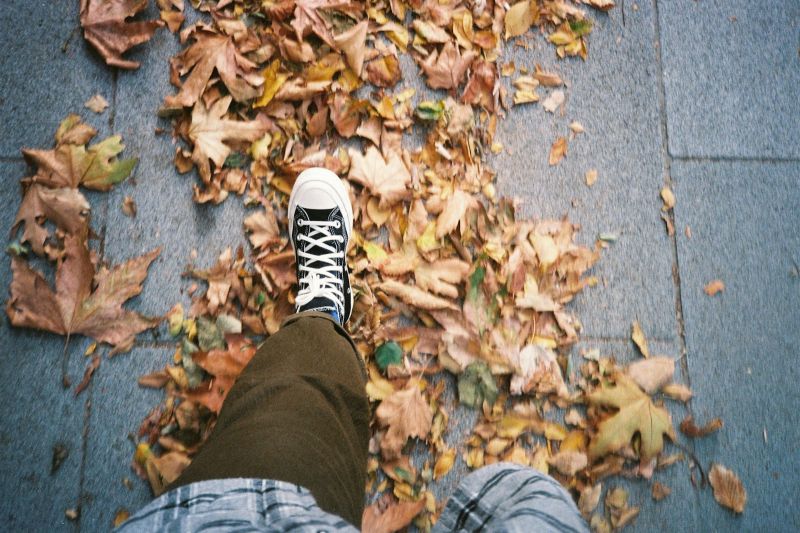 Un pas sur un trottoir couvert de feuilles mortes