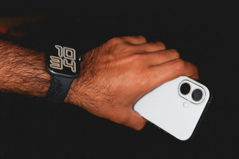 Une main portant une montre connectée tient un téléphone