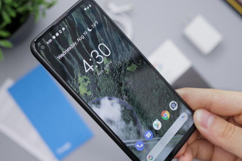 Une main tient un téléphone Android affichant l’écran d’accueil